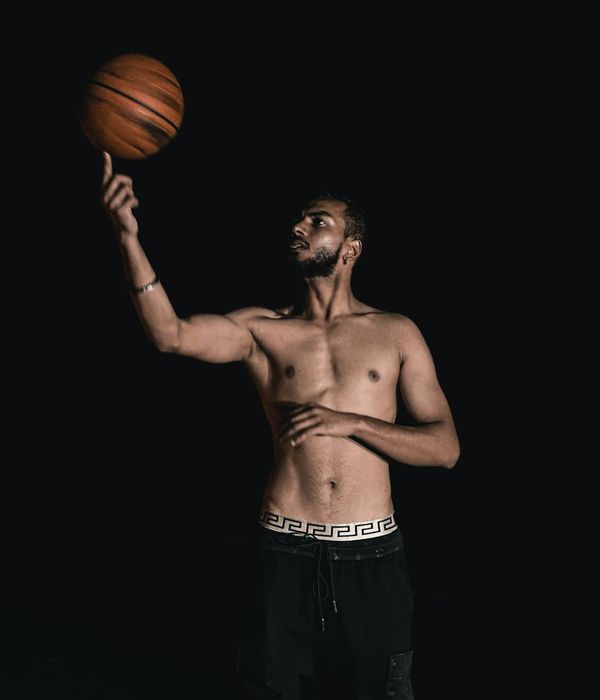 Man performing a controlled strength exercise in a dark studio setting.